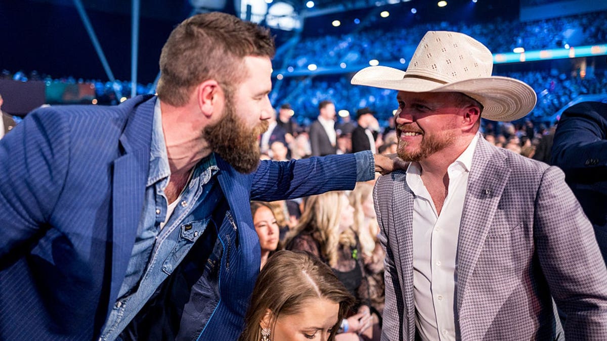 Jordan Davis pats fellow country music star Cody Johnson on the shoulder