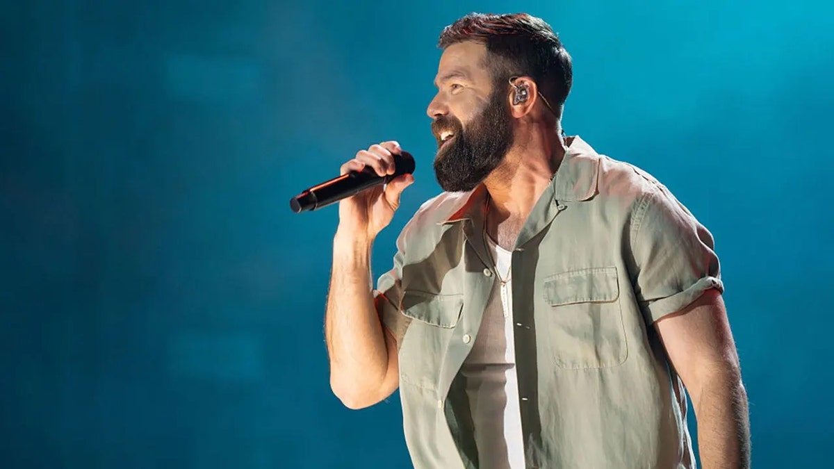 country star Jordan Davis sings into a microphone