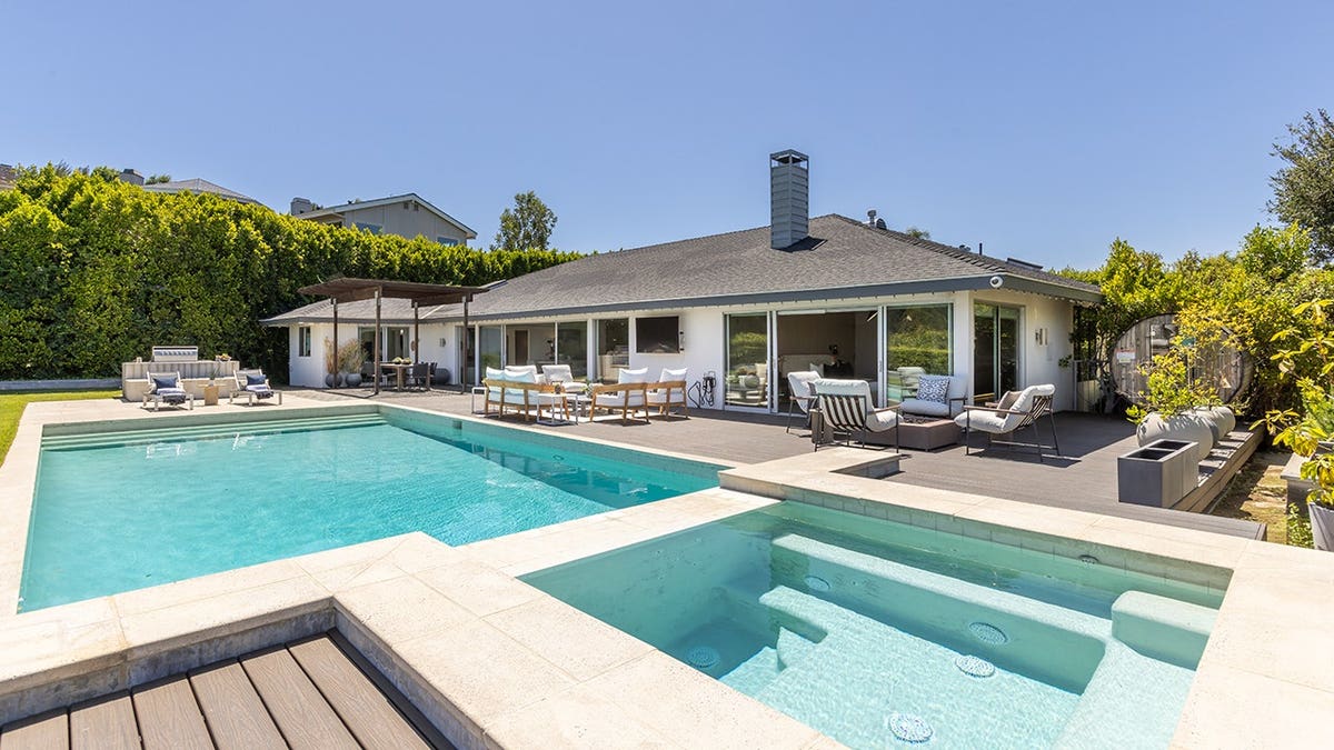 A backyard with a large swimming pool and jacuzzi.