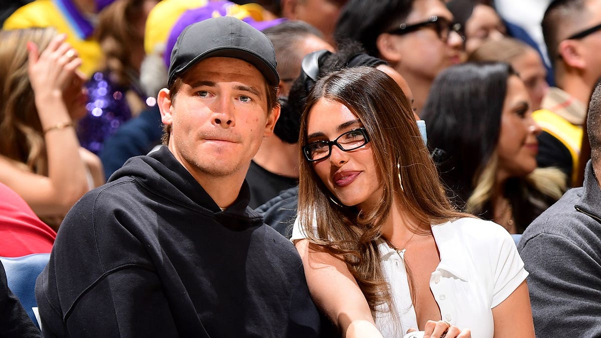 Justin Herbert and Madison Beer sit at a basketball game in Los Angeles.