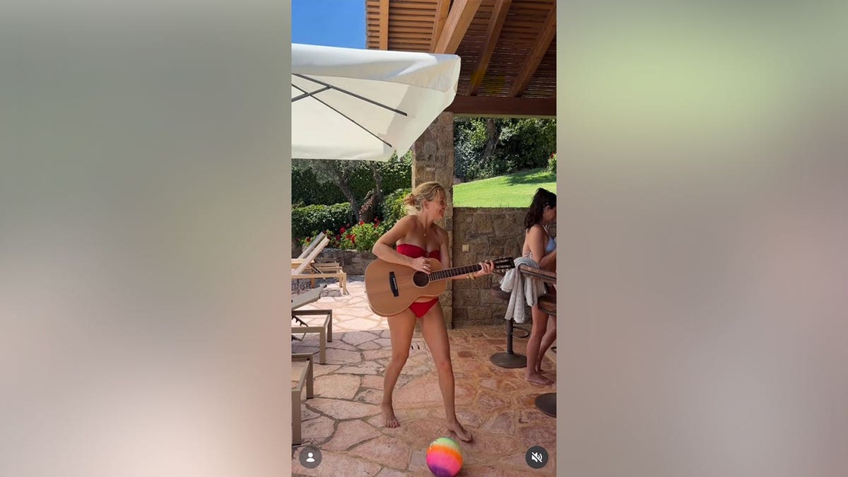 Kate Hudson sosteniendo una guitarra mientras está en bikini rojo.