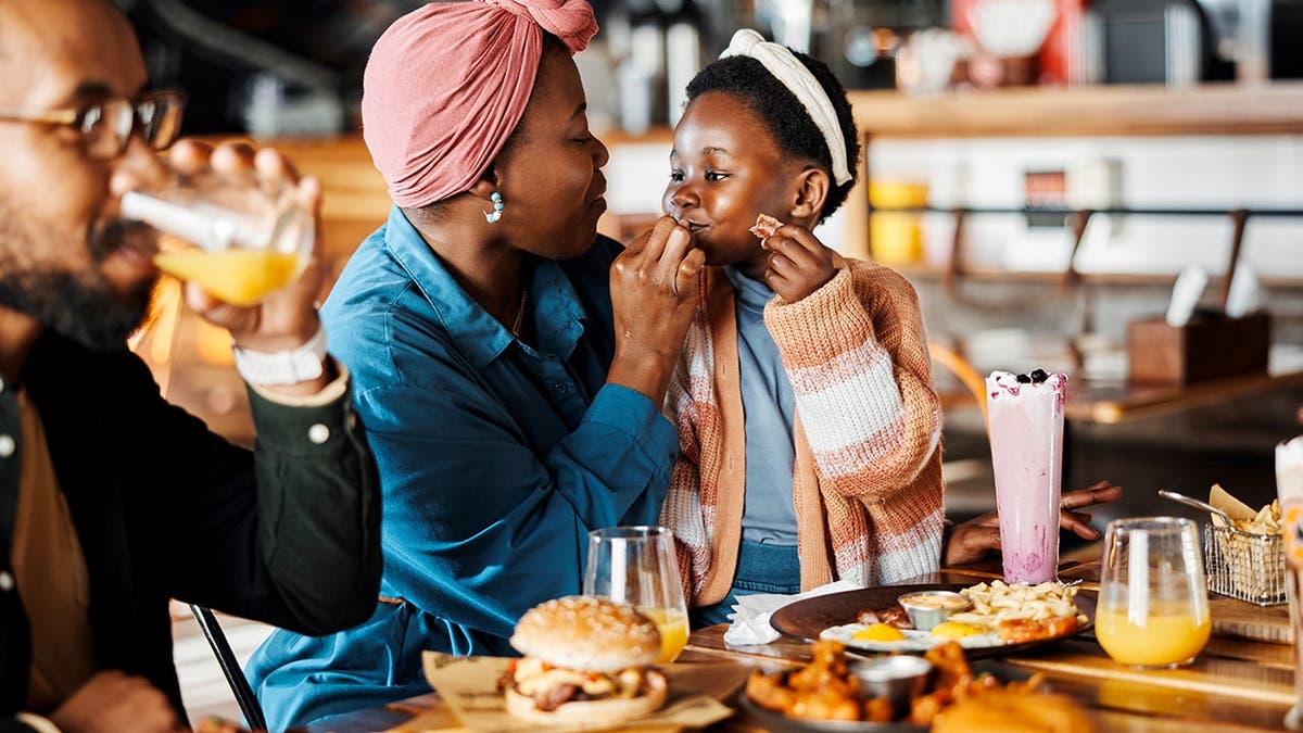 A child enjoys a meal with her family at a restaurant.