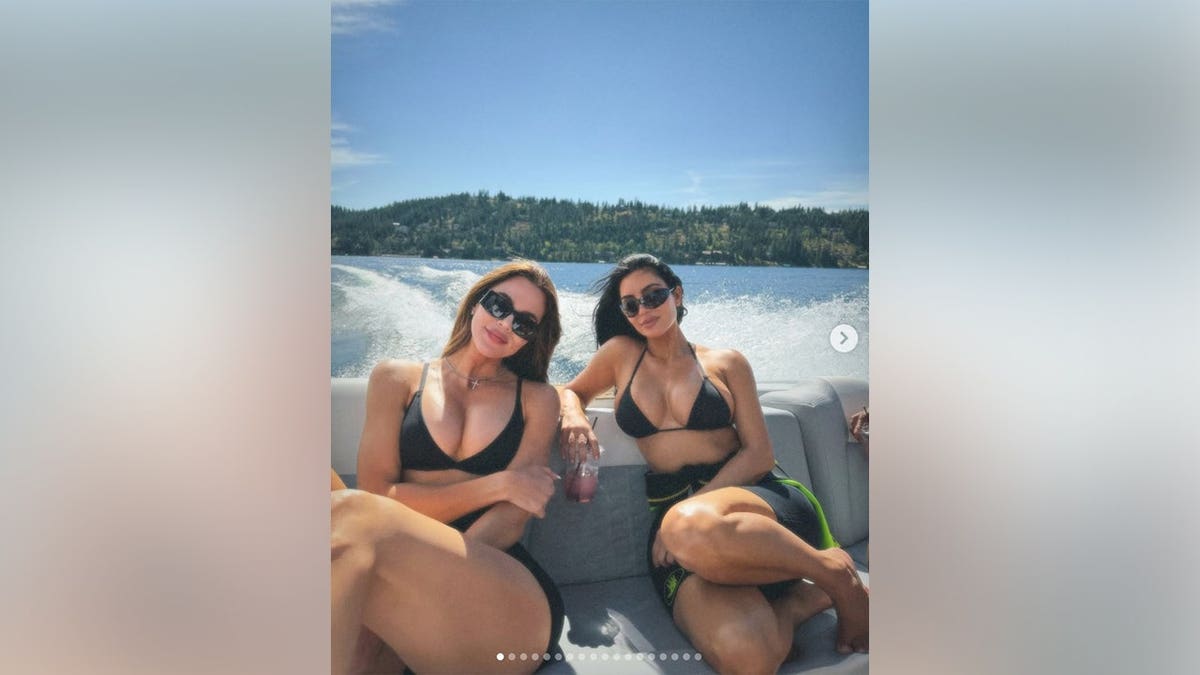 Kim Kardashian and her sister Khloe Kardashian smiling together while on a boat in a lake.