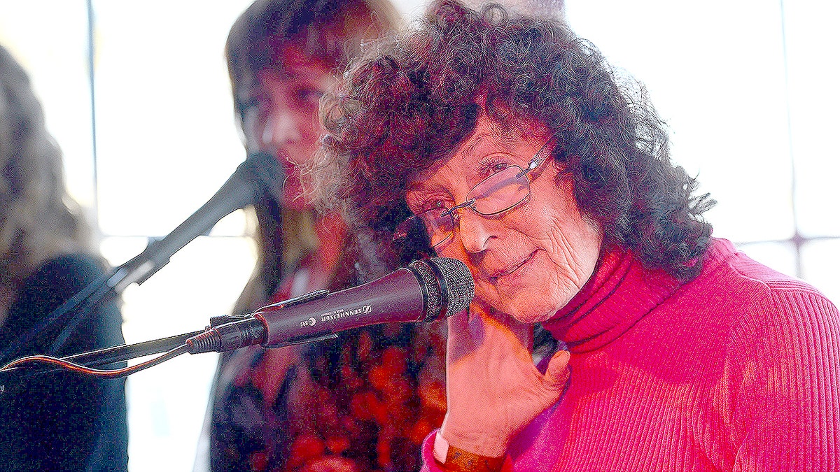 Linda Perhacs performs onstage with a microphone at the Way Over Yonder Festival.