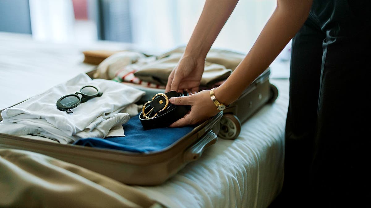 Una mujer dobla ropa en una maleta.