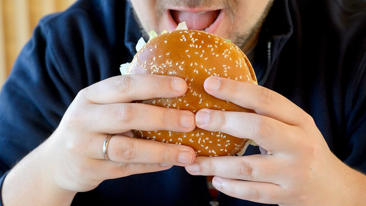 A man prepares to bite into a Burger King Whopper.