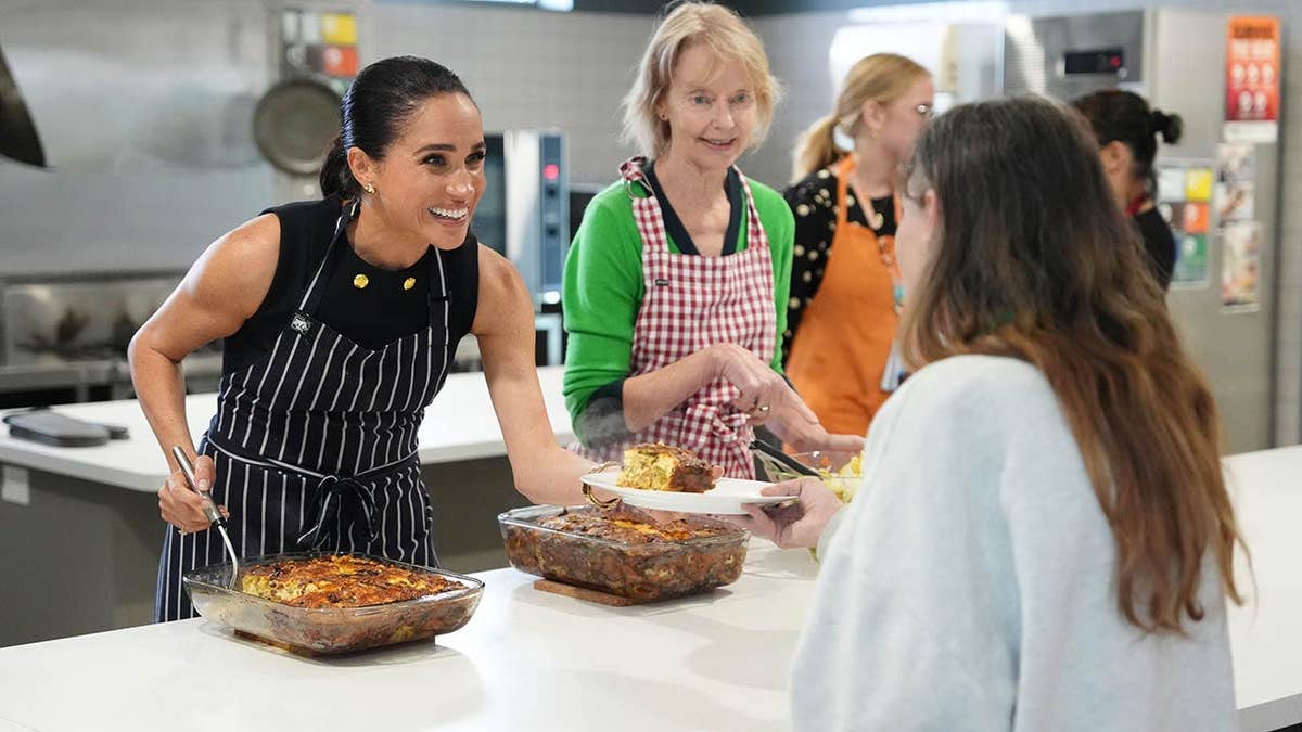 Meghan, Duchess of Sussex serves lunch to a resident at McAuley Community Services for Women.