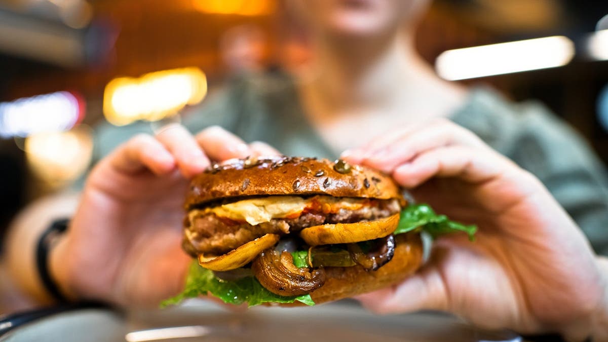 A person holds a mushroom burger.