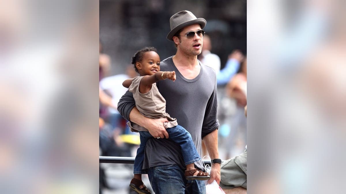 Brad Pitt stands with Zahara Jolie-Pitt, Pax Jolie-Pitt and Maddox Jolie-Pitt at a playground.