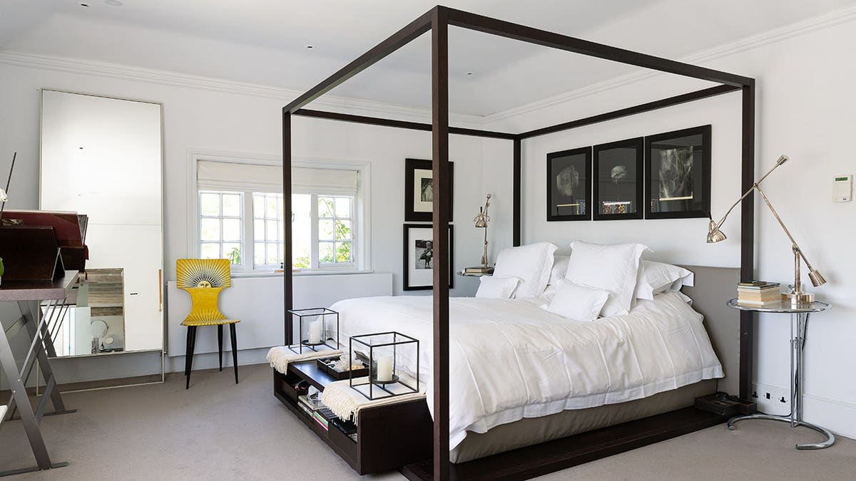 A bedroom with a white bed with black bedframe.