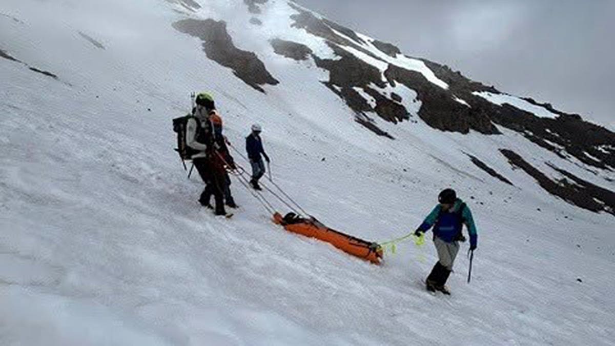 Climbers lower an injured Mount Shasta climber into a rescue litter