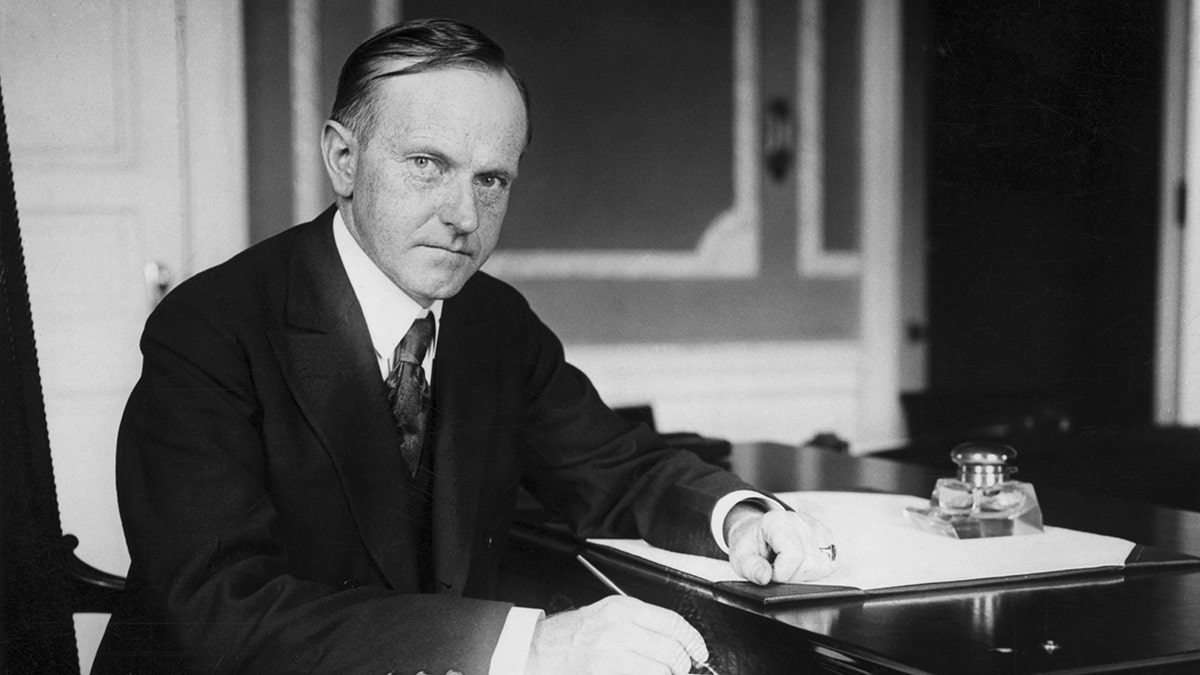 Calvin Coolidge sitting at his desk.