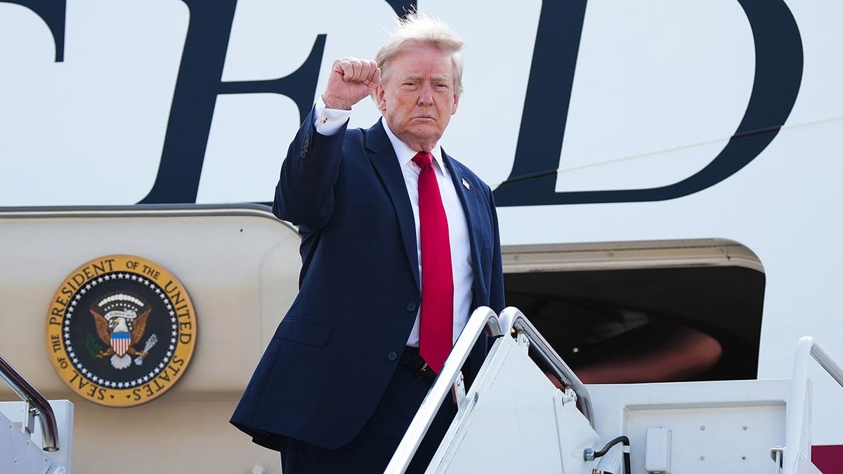 President Donald Trump pumps his fist in the air as he boards Air Force One