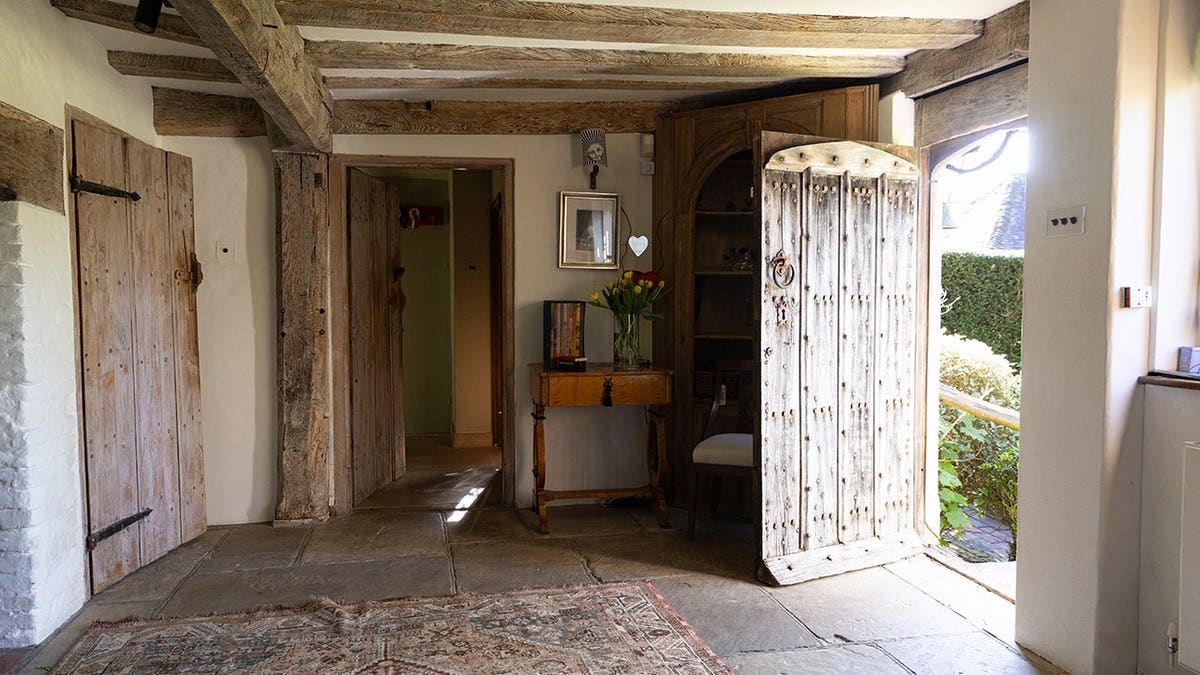 An open front door and ceiling with exposed wooden beams.