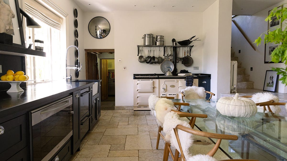 A kitchen connected to a dining room with white fluffy chairs.