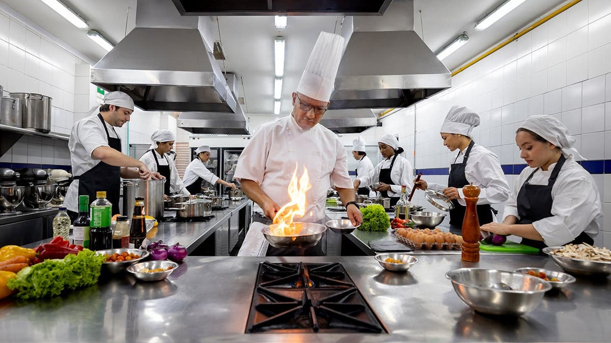 A group of chefs cooks in a restaurant kitchen.