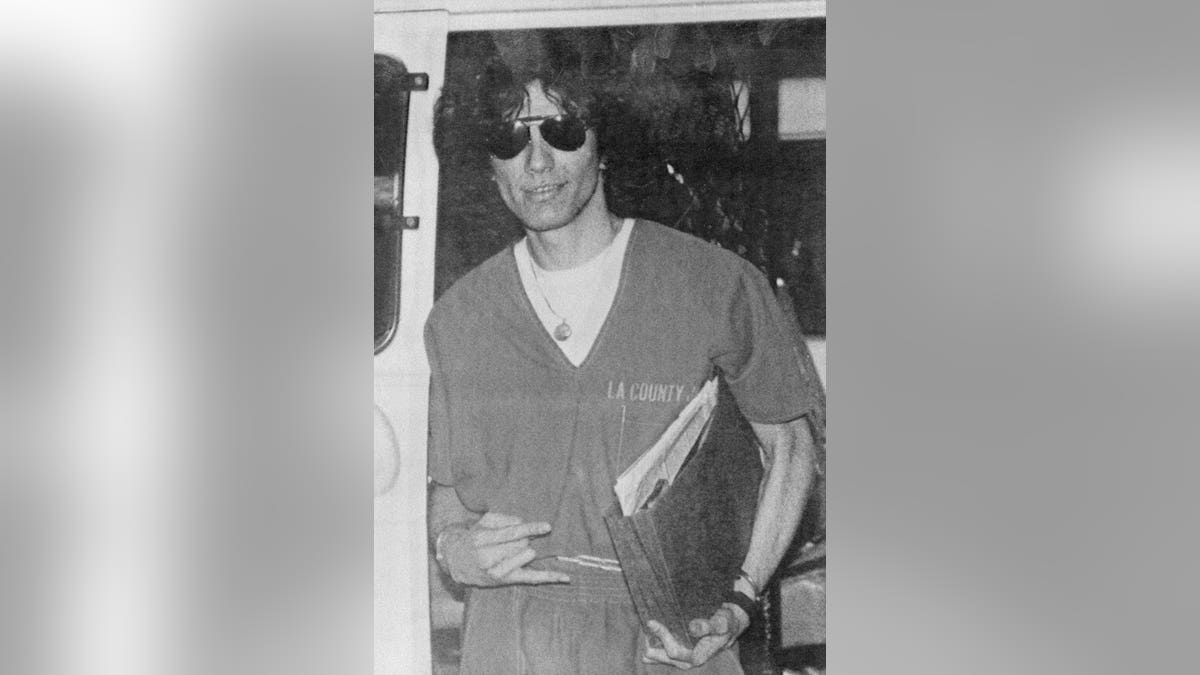 Richard Ramirez flashes a two-finger sign while being led from courthouse.