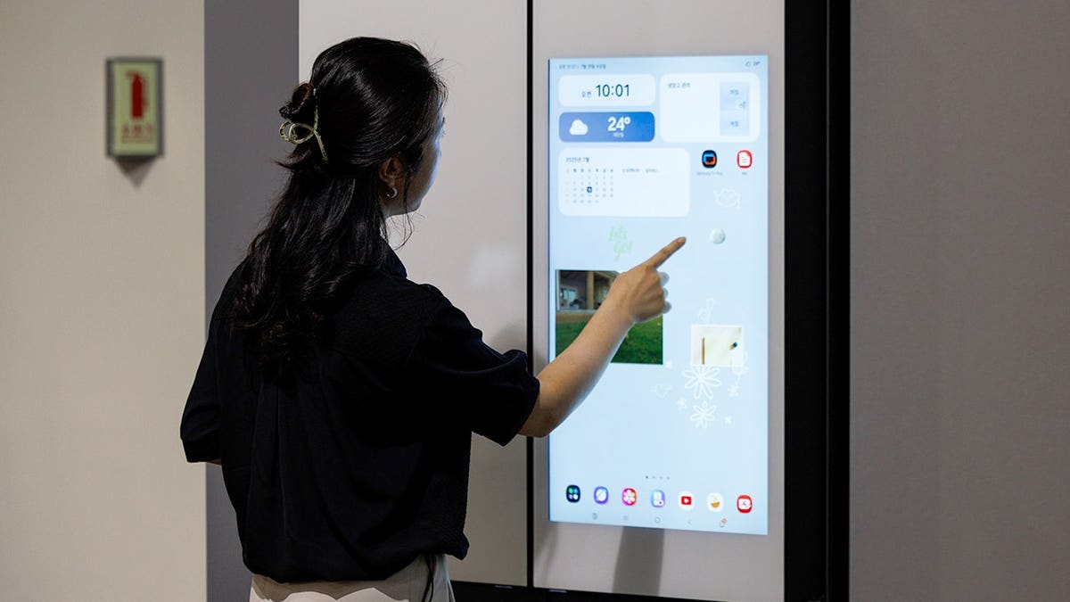 A woman interacts with the screen on a smart refrigerator.