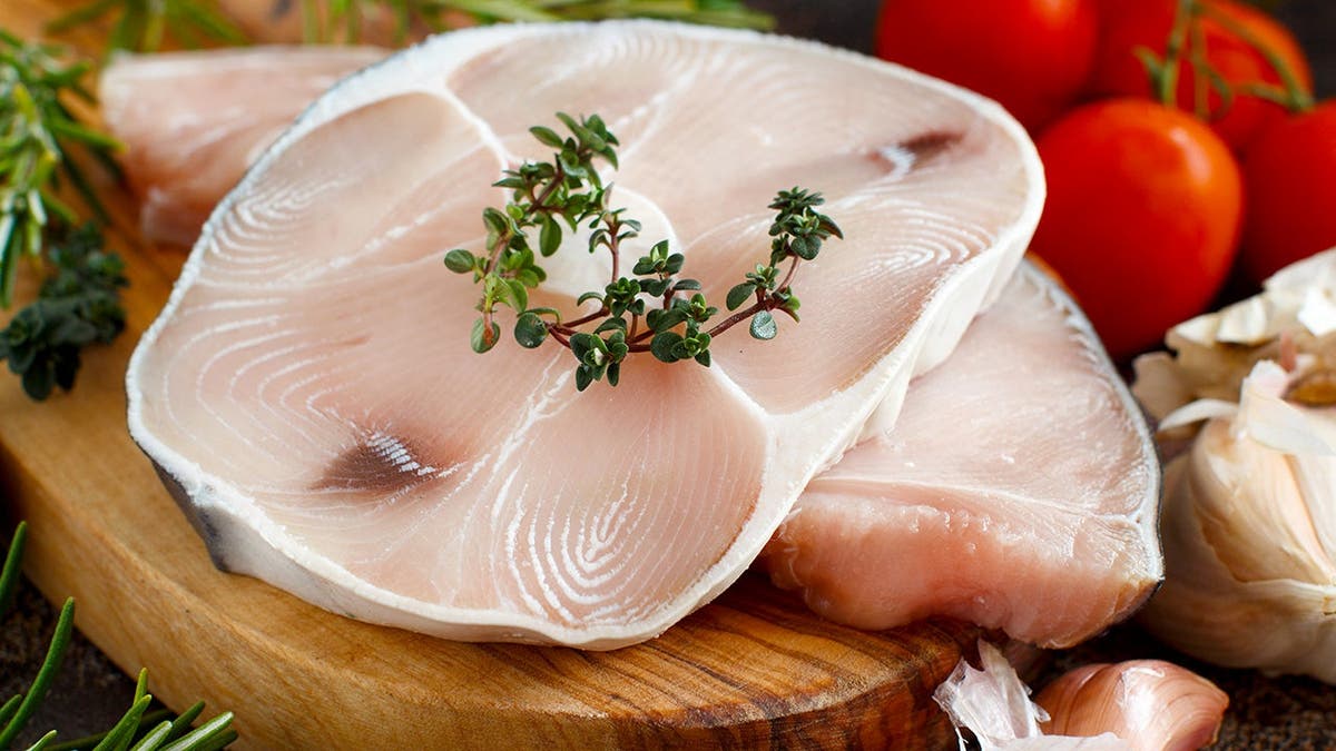 Two shark steaks sit on a plate.