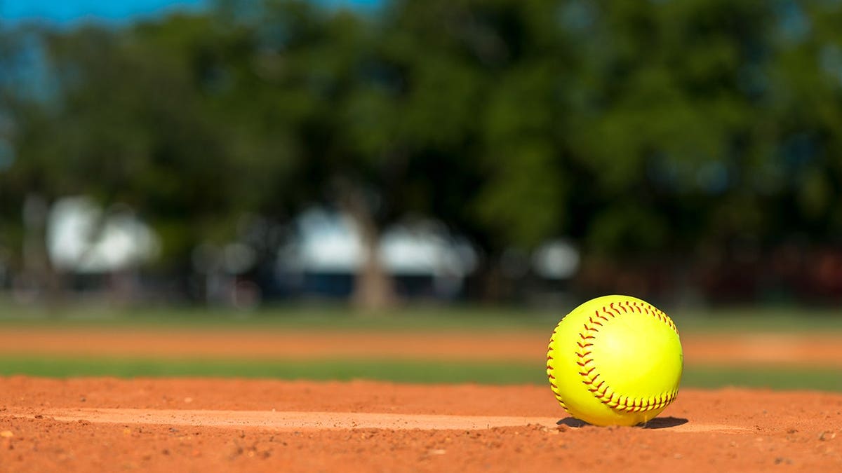 Softball sits on a baseball diamond.