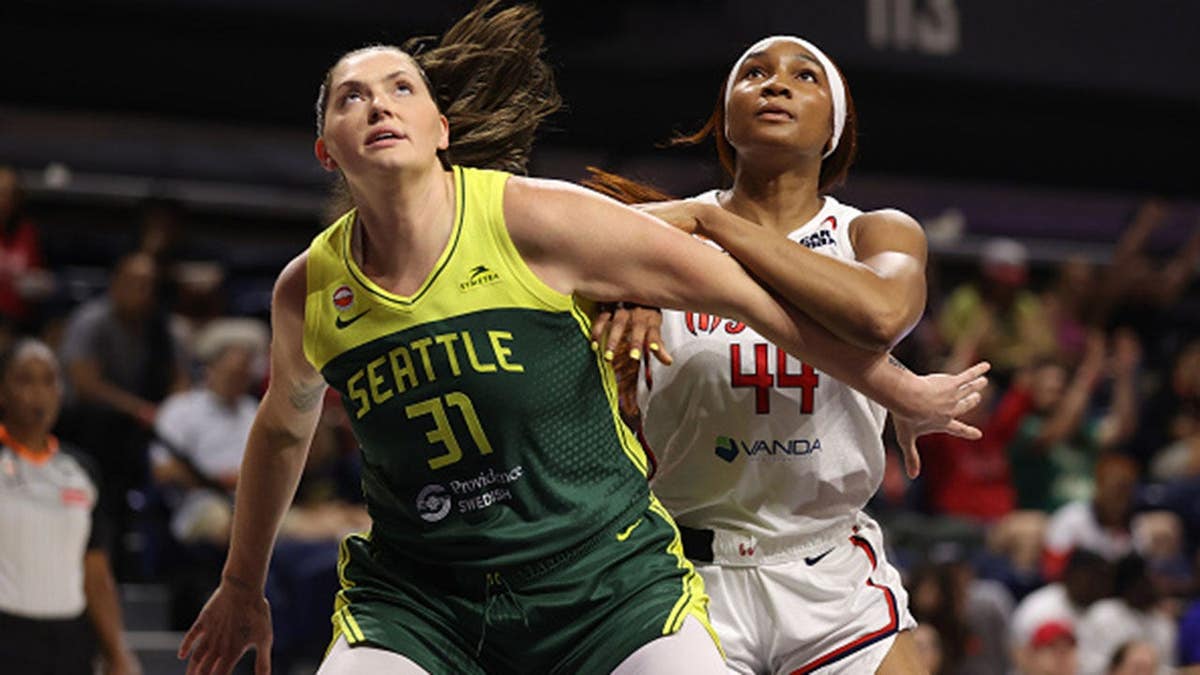 Stefanie Dolson and Kiki Iriafen reach for a rebound during a WNBA game.