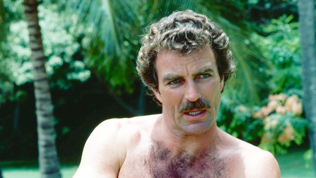 Tom Selleck stands as Magnum, P.I. in a television series scene.
