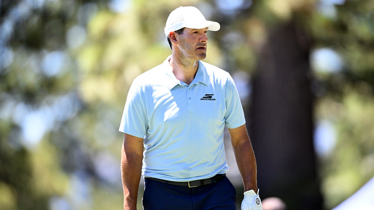 Tony Romo stands on a golf course.