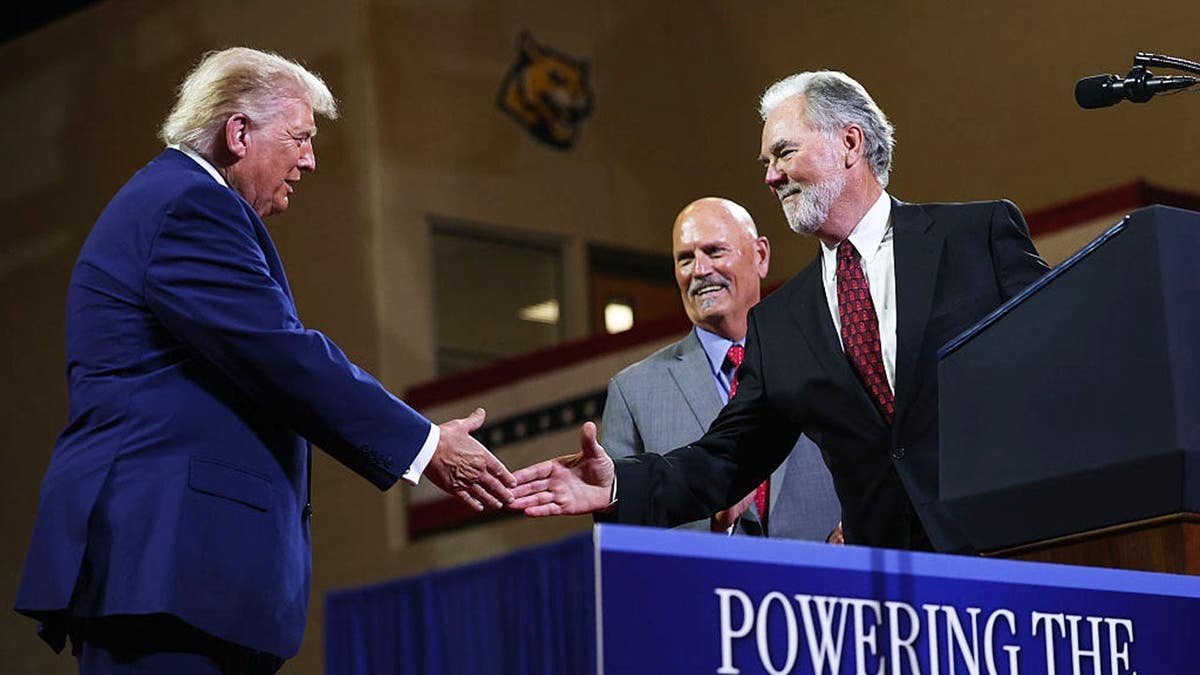 President Donald Trump shakes hands with Mike Plant on stage at Wheeler High School in Marietta, Georgia.
