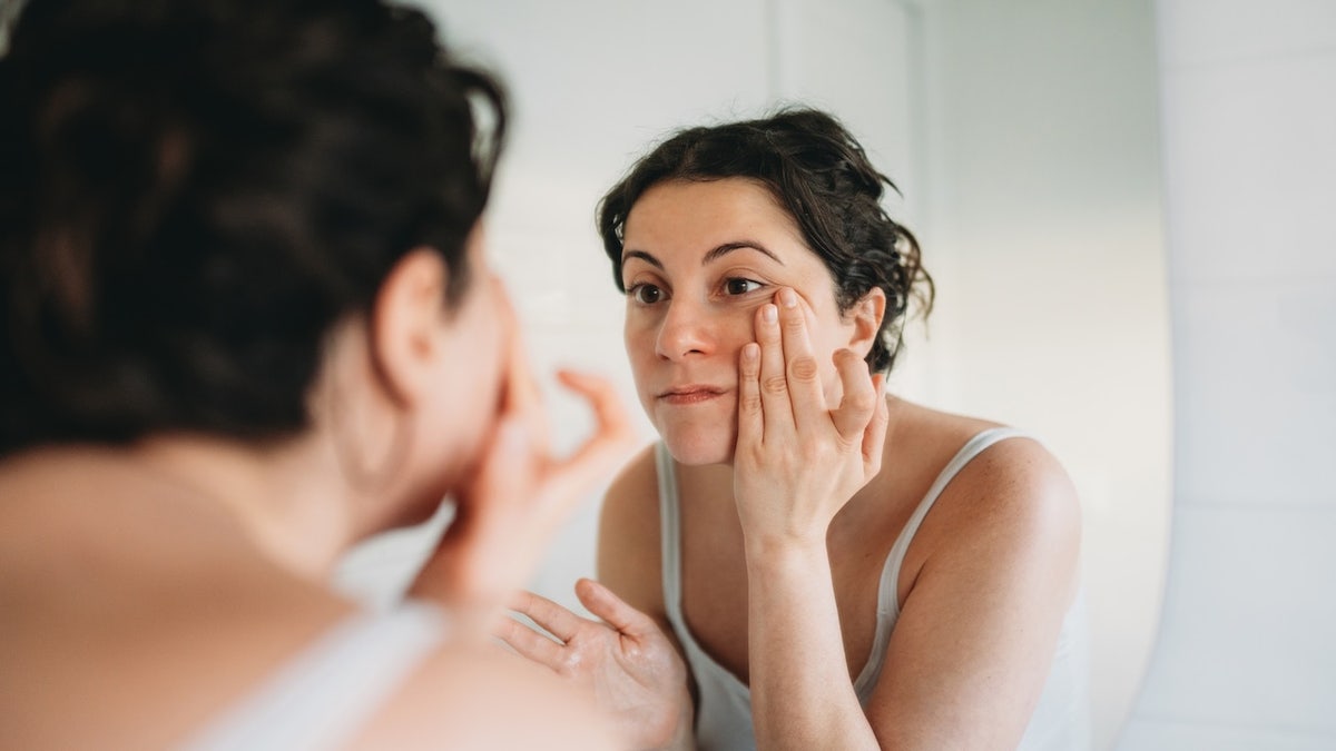 Woman looking at skin in mirror