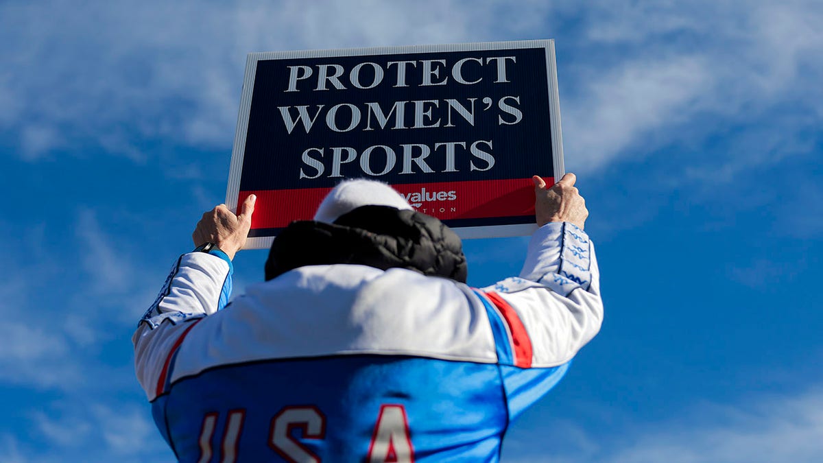 protestor holds up women's sports sign