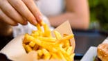 A person eats French fries.