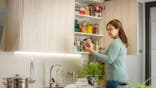 A woman looks at food in her pantry.