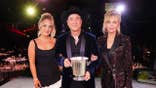 Lily Black, Clint Black and Lisa Hartman Black standing together and holding an award in Nashville.