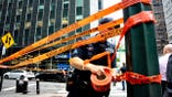 Police officer wrapping caution tape around pole and street