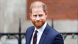 Prince Harry in a dark blue suit walking outside of London's High Court.