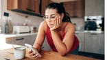Woman looking at smartphone in kitchen