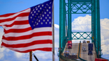 Trucks and cars are seen on the Vincent Thomas Bridge as steady winds blow a U.S. flag.