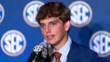 Arch Manning, quarterback for the Texas Longhorns, speaks at a podium.