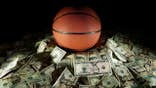 Basketball sits on a pile of cash.