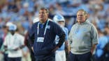 Bill Belichick and Michael Lombardi stand on the sideline at Kenan Memorial Stadium.