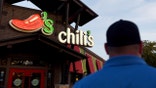 A Chili's customer prepares to enter the restaurant. The Chili's logo appears above the door.