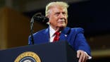 President Donald Trump speaks at a podium at Wheeler High School.