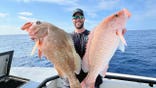 man on boat holds up two large fish