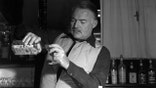 Ernest Hemingway pours Gordon's Dry Gin into a glass.