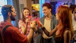 Young adults clink glasses at a house party