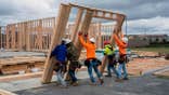 Workers are seen framing a home on a construction site.