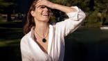 A woman smiles while wearing the iKairos device as a pendant.