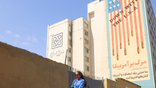 An Iranian woman walks past an anti-US banner in Tehran on July 19, 2026.