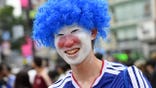 Man dressed in a blue Japan soccer uniform, a blue wig and face paint.