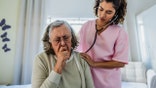 Doctor examining a senior woman at home
